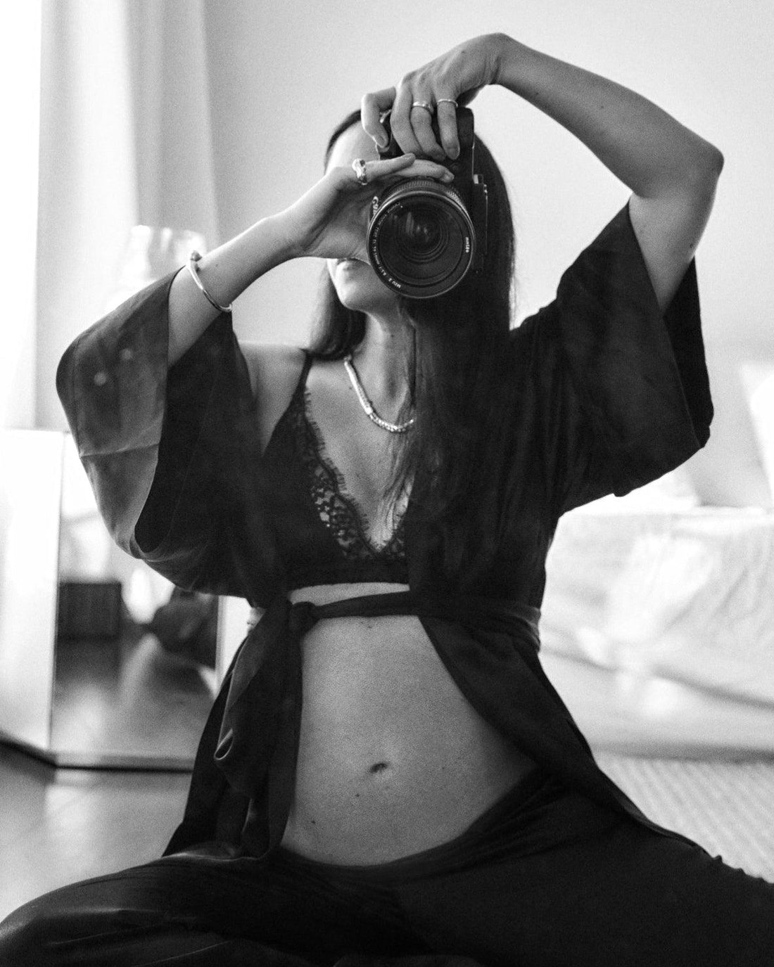 Woman in black Gingerlilly Sleepwear robe taking a mirror self-portrait in a bedroom