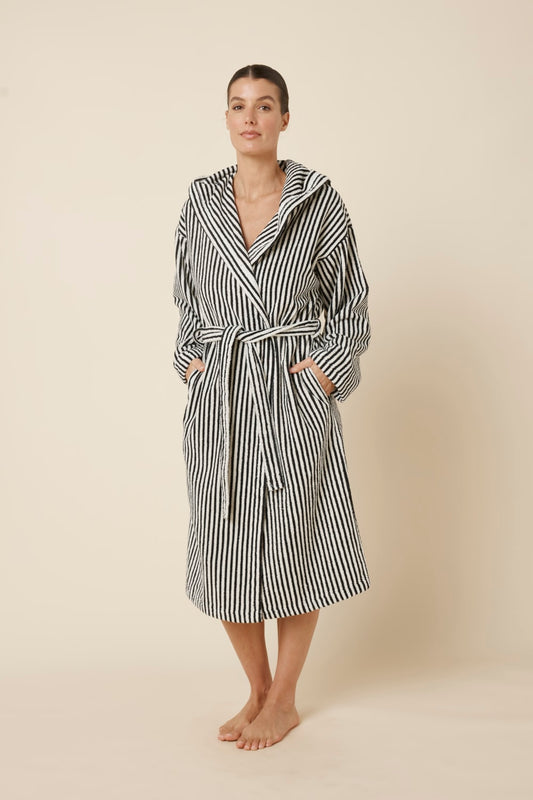 Woman wearing a striped adriana terry towel robe in black colour side on view with hands in pockets