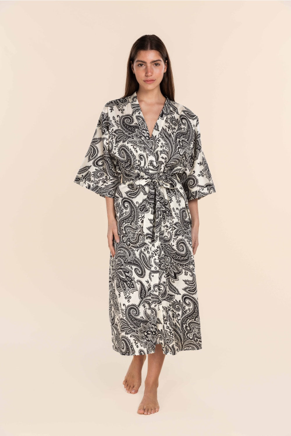Woman wearing a black and white patterned robe on a beige background