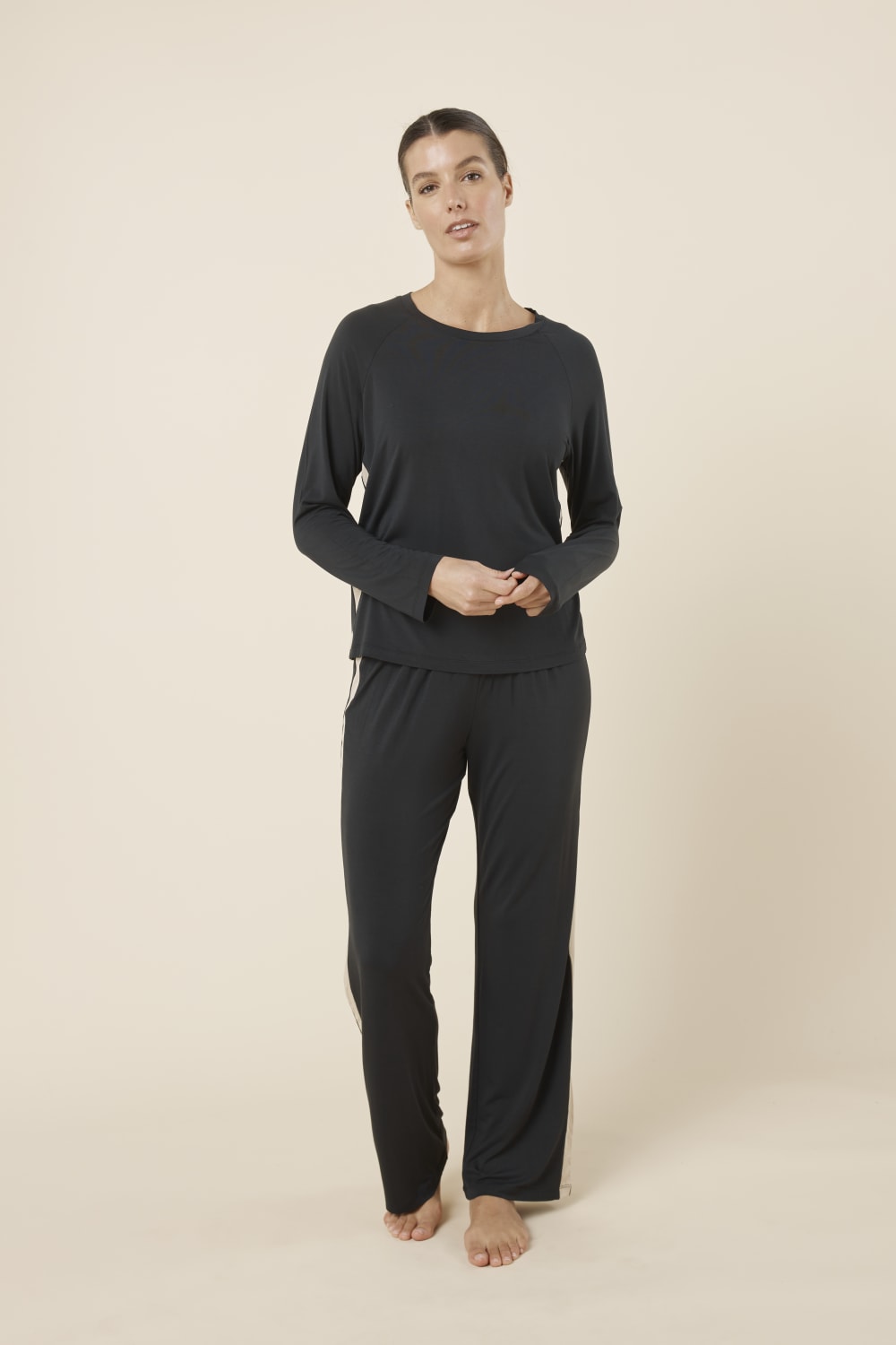 Woman wearing Anya Bamboo Sporty PJ Set Black standing in a relaxed pose, highlighting the soft bamboo fabric, long sleeves and comfortable straight pants.