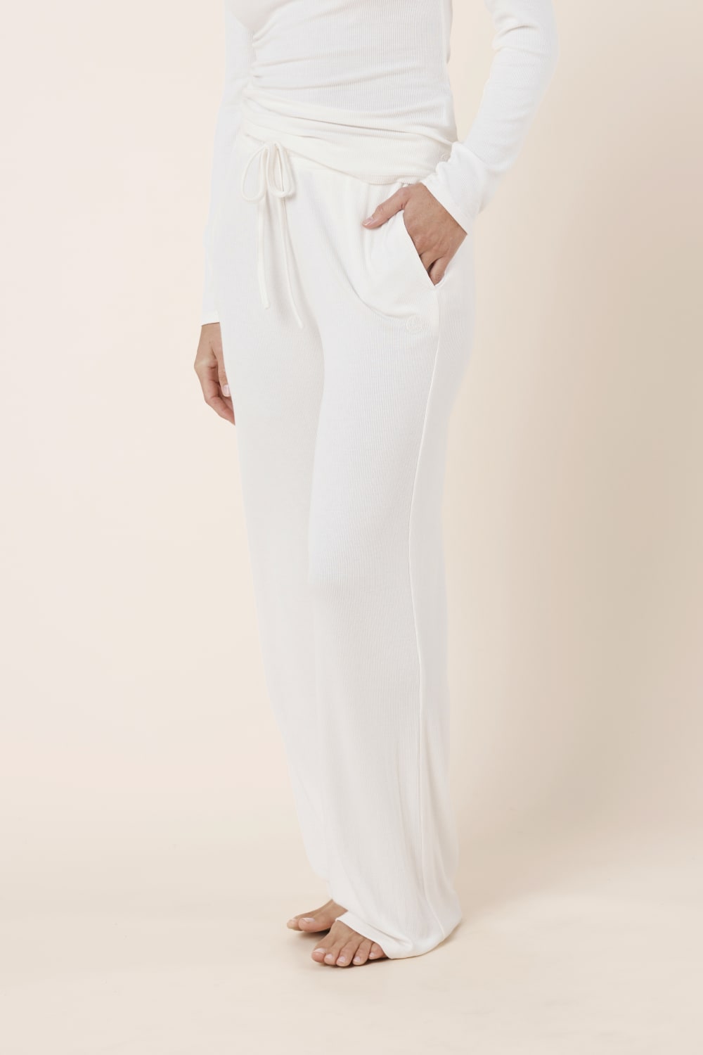 Woman wearing Athens Ribbed Long Pants Ivory, side view showing relaxed wide leg fit and soft ribbed texture