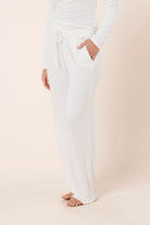 Woman wearing Athens Ribbed Long Pants Ivory, side view showing relaxed wide leg fit and soft ribbed texture
