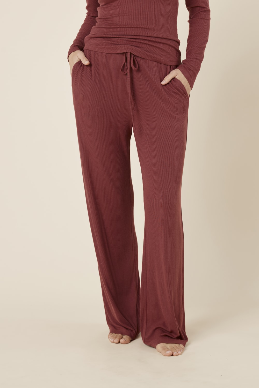 Woman wearing the athens ribbed Long pant burgundy from front view with hands in pockets