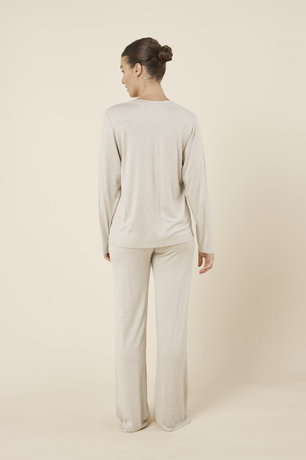 Woman wearing a brianna lounge set oatmeal on a plain beige background back view