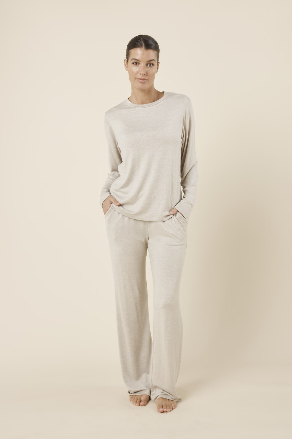 Woman wearing a brianna lounge set oatmeal on a plain beige background with hands in pockets