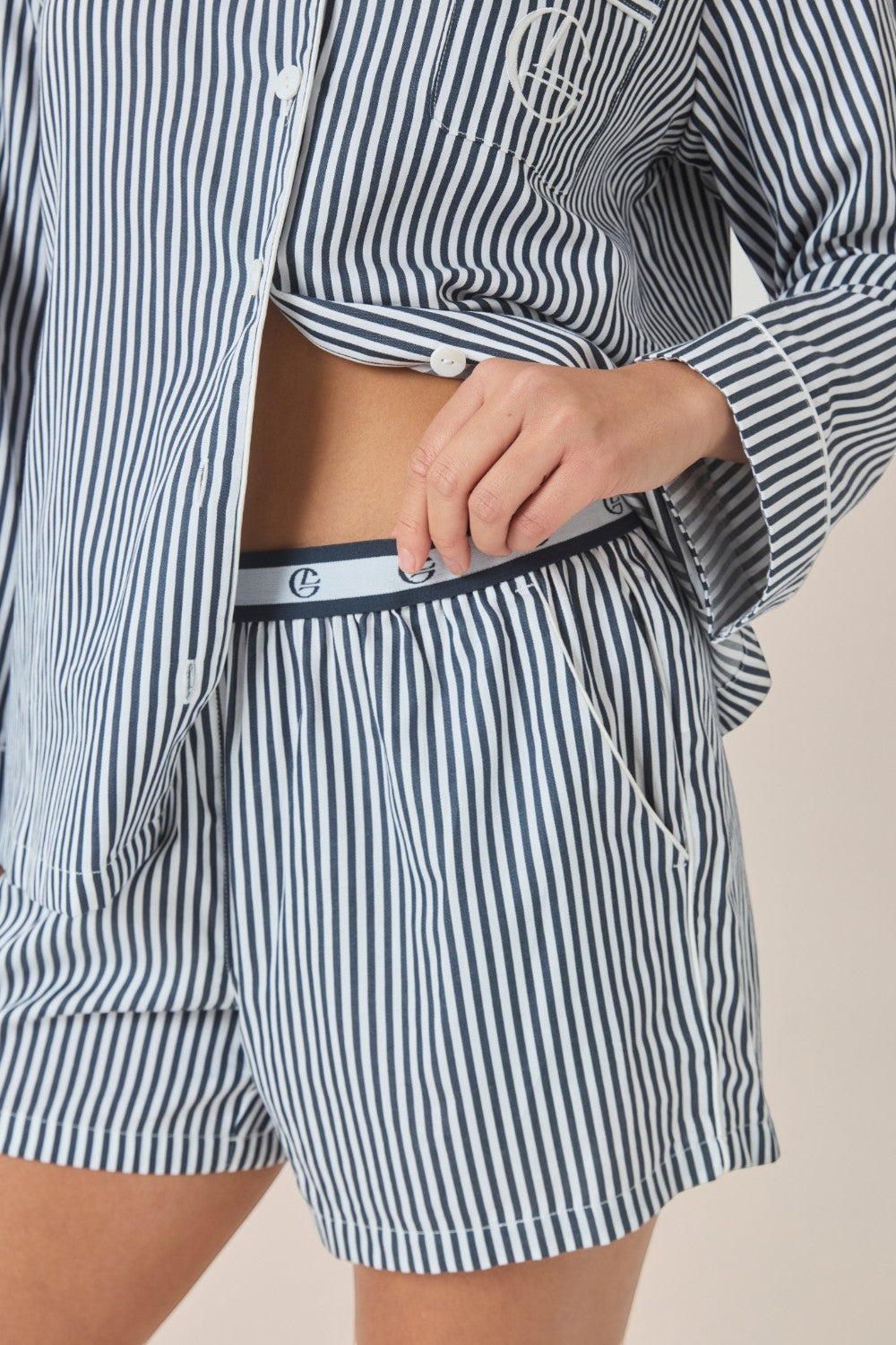 Close-up of a navy and white striped pajama shirt and shorts, showing the branded elastic waistband and side pocket.