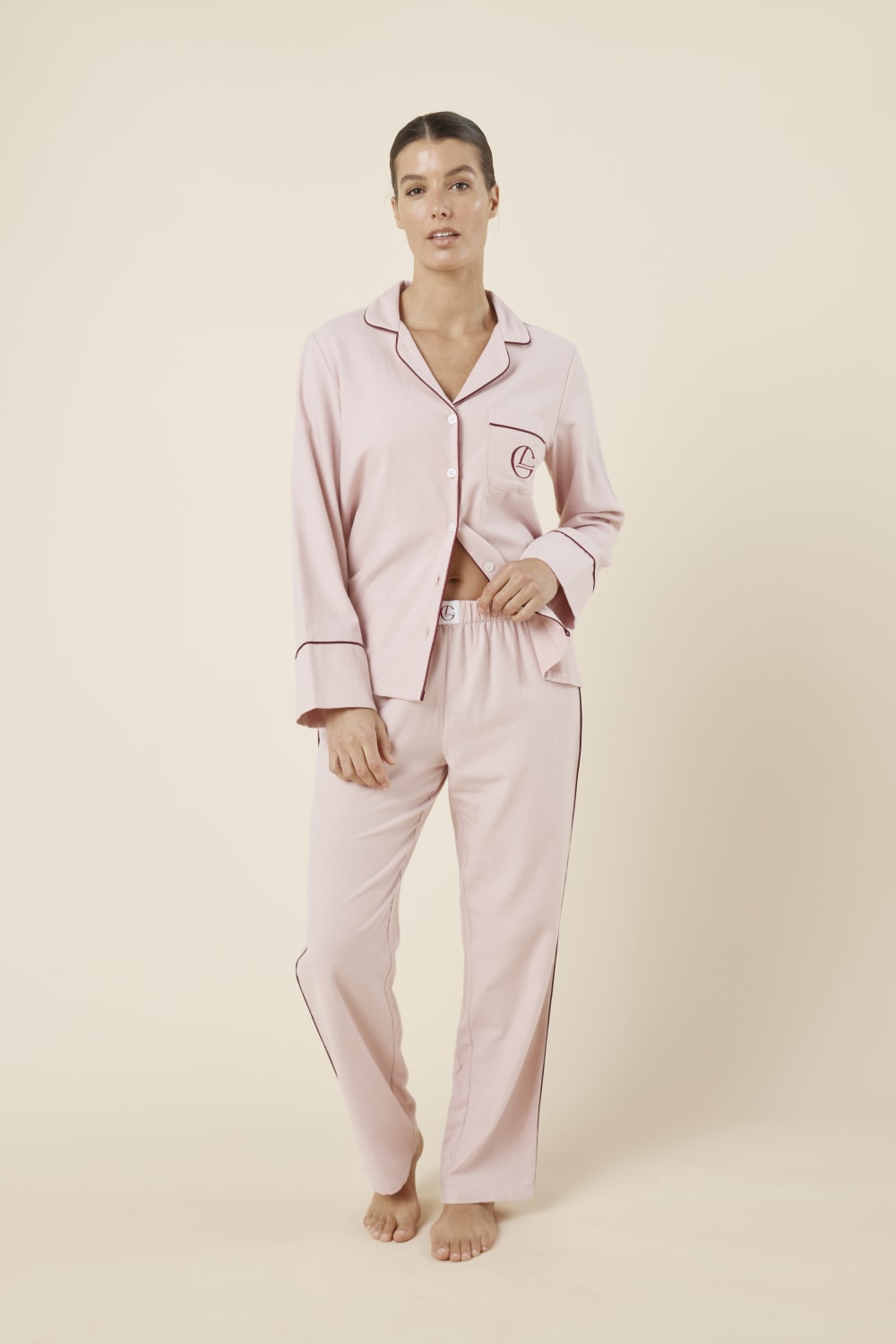 Woman wearing light pink isabella brushed cotton pyjama PJ set with a small red logo on a beige background front on view