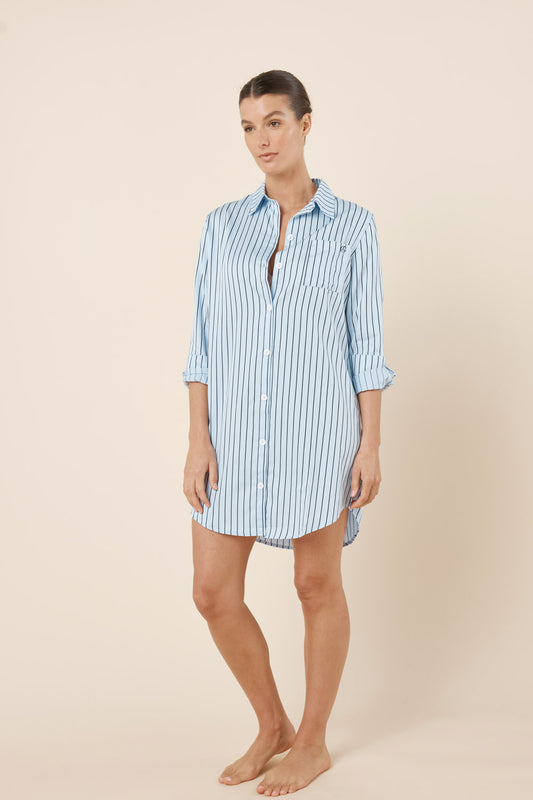 Woman wearing a light blue and white striped shirt dress on a beige background