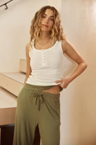 Woman wearing Liberty Ribbed Singlet Henley Top Ivory, ribbed sleeveless henley lounge top with button neckline