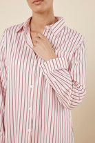 Woman wearing a pink striped Lolita Stripe Night Shirt dress against a beige background front on close view with arm near neck
