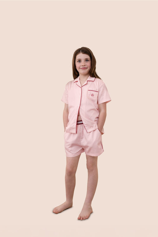 Young girl wearing a pink pajama set on a beige background
