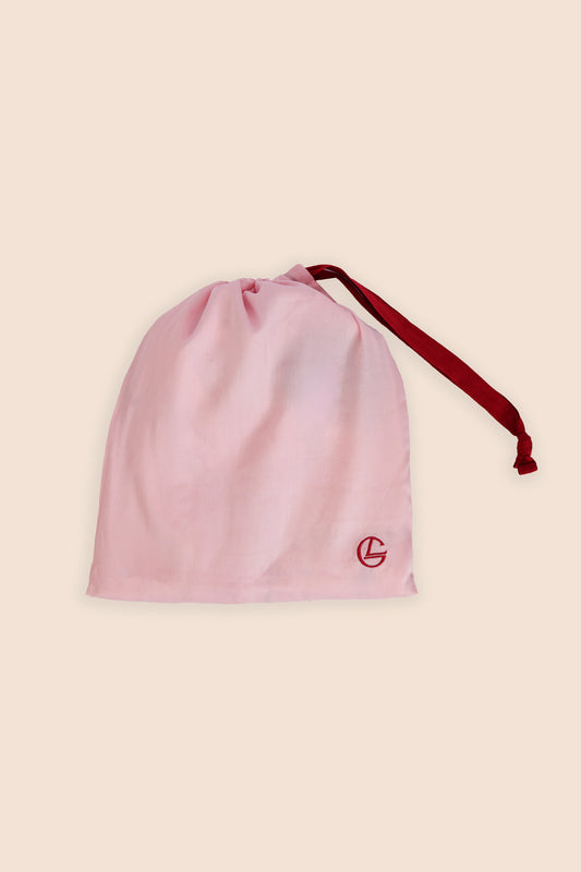 Pink drawstring bag with a red logo on a beige background