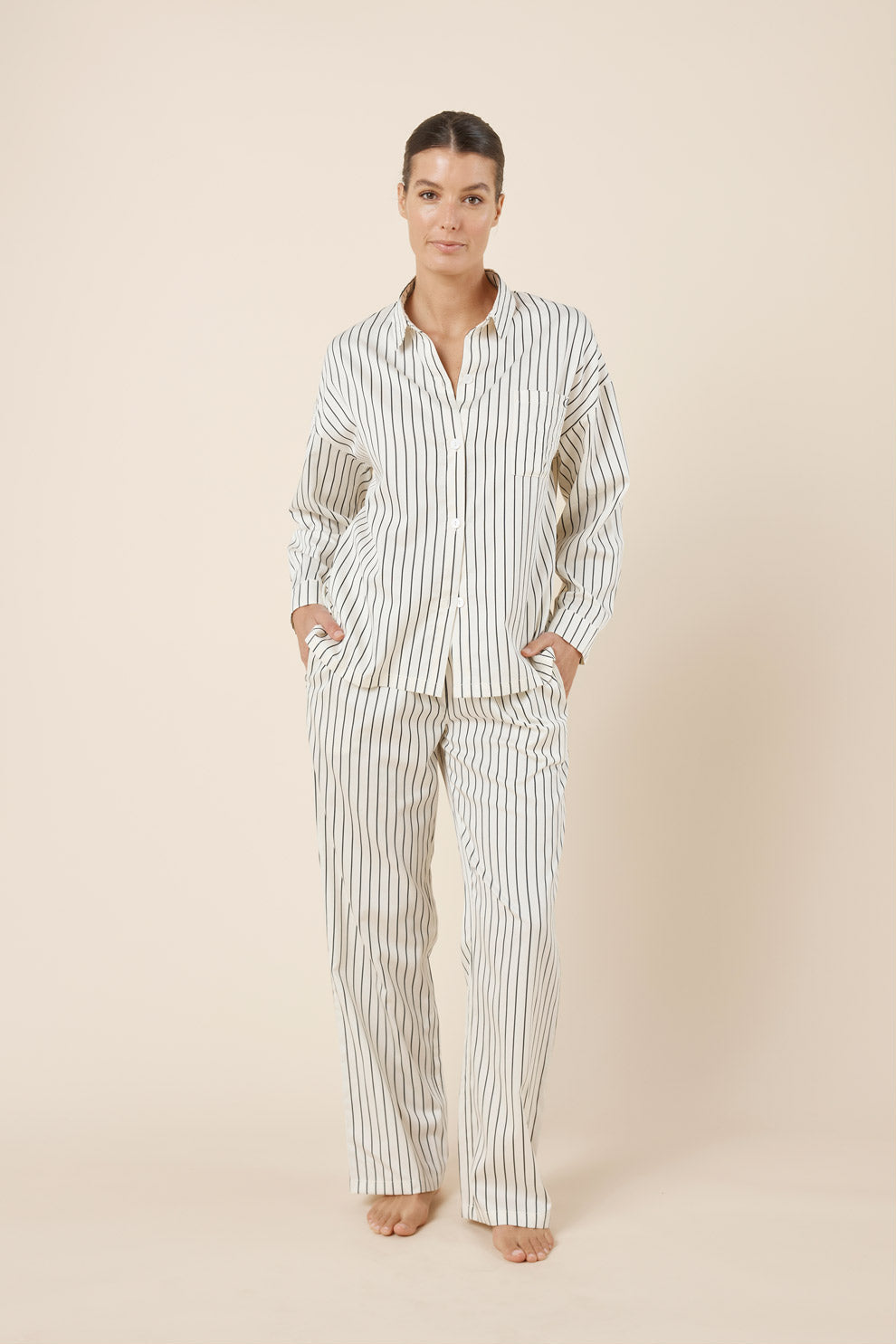 Woman wearing a striped pajama set against a beige background