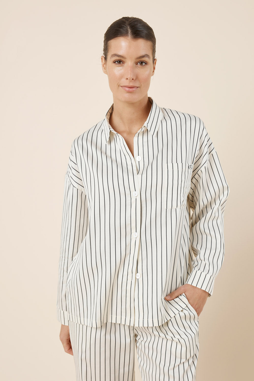 Woman wearing a striped pajama set against a beige background