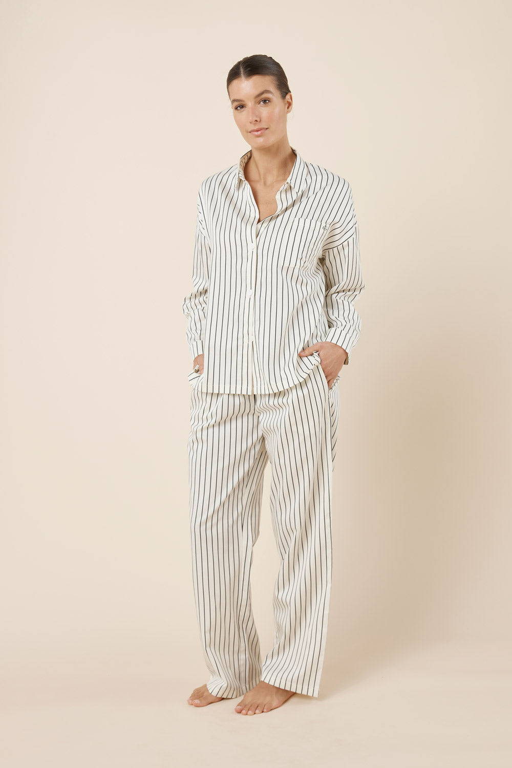 Woman wearing a striped pajama set on a beige background