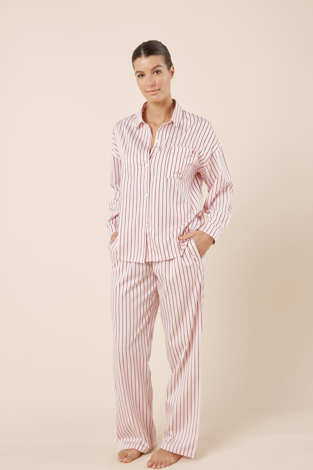 Woman wearing a red and white striped pajama set on a beige background
