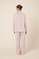 Woman wearing a pink striped willow cotton stripe pyjama PJ set in set on a beige background and back view