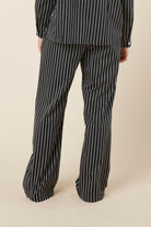 Person wearing Willow Cotton Striped Pant Black and white pyjama set on a beige background back view