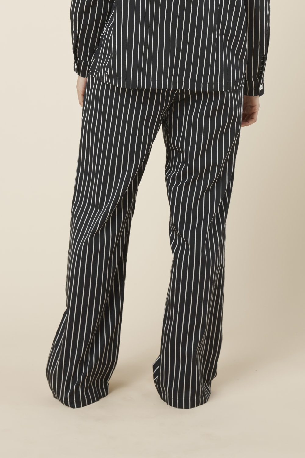 Person wearing Willow Cotton Striped Pant Black and white pyjama set on a beige background back view