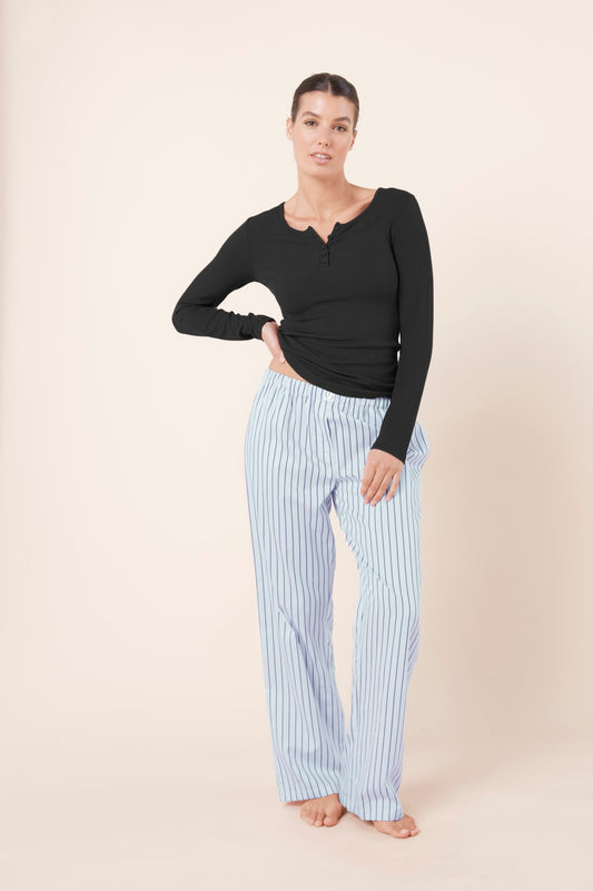 Woman wearing a black long-sleeve top and Willow Cotton Striped Pants in Blue front view on a beige background
