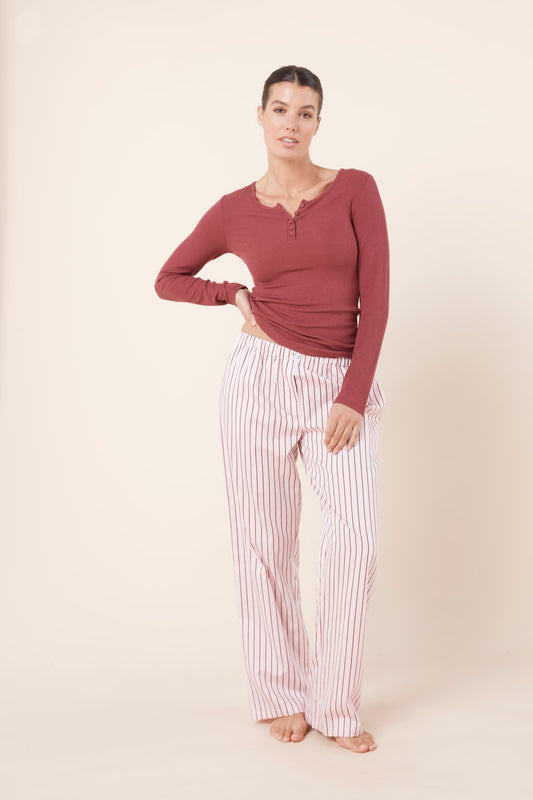 Woman wearing a mauve long-sleeve top and Willow Cotton Striped Pant in Pink and white stripe on a beige background