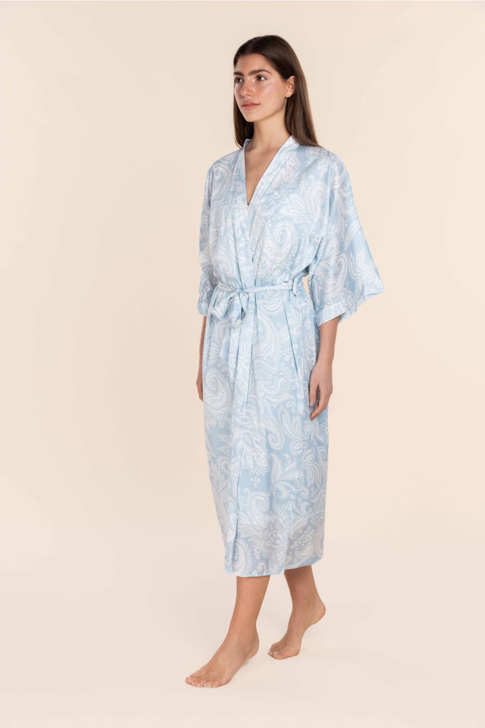 Woman wearing a light blue patterned robe on a beige background
