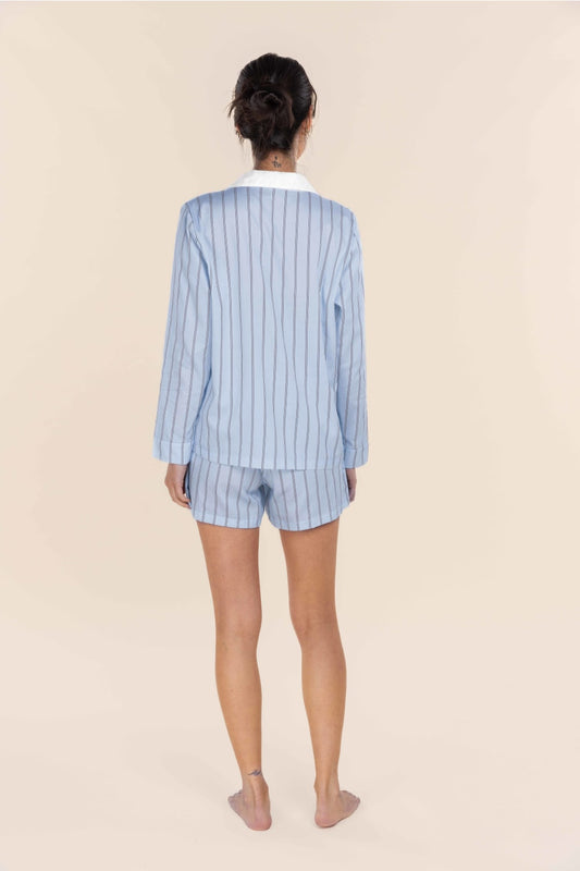 Person wearing a light blue pinstripe pajama set on a beige background