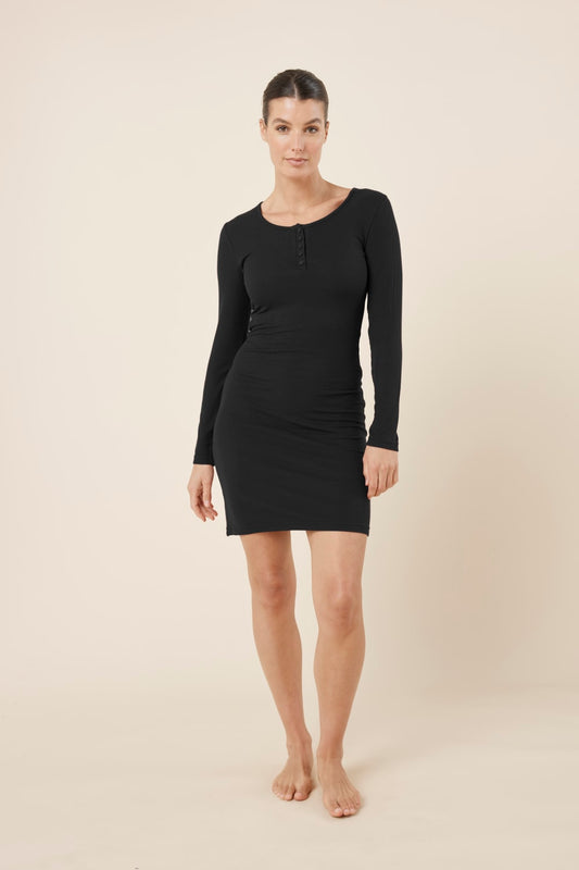Woman wearing a black bonnie ribbed long sleeve midi henley nightdress against a beige background