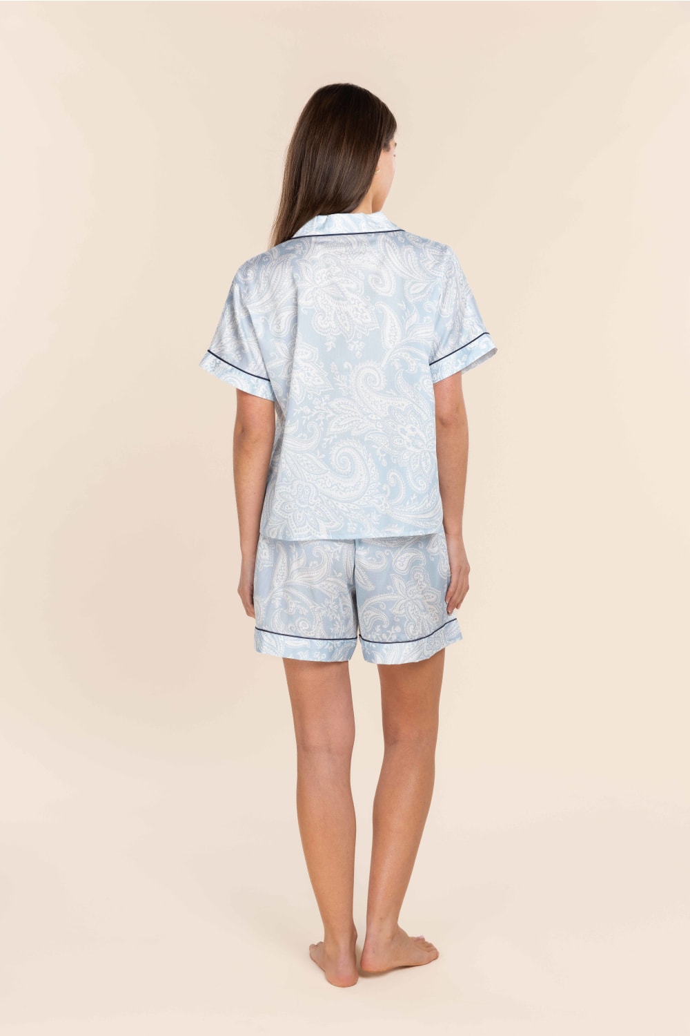 Woman wearing a light blue pajama set with a subtle pattern on a beige background