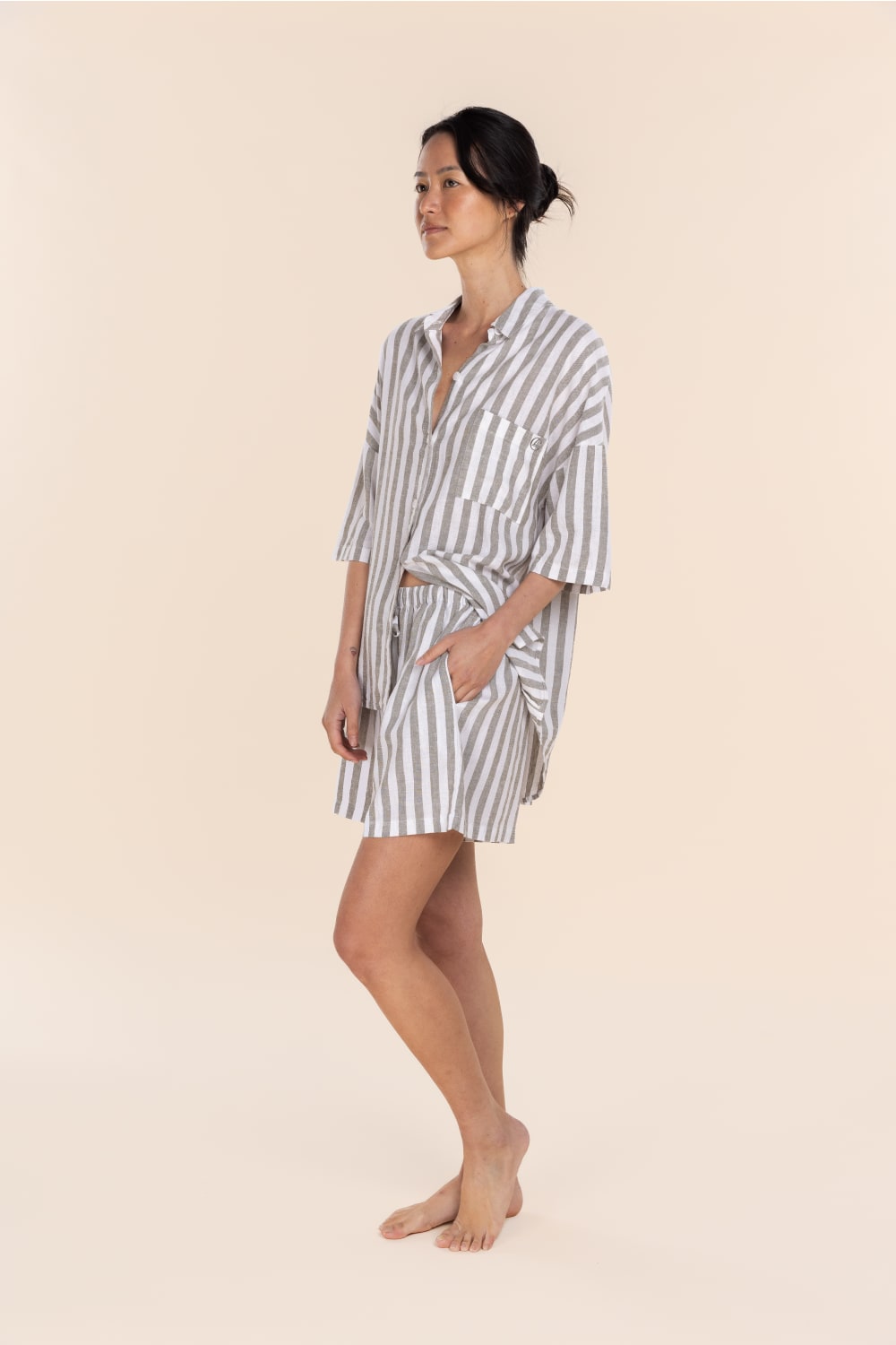 Woman wearing a striped shirt and shorts set on a beige background