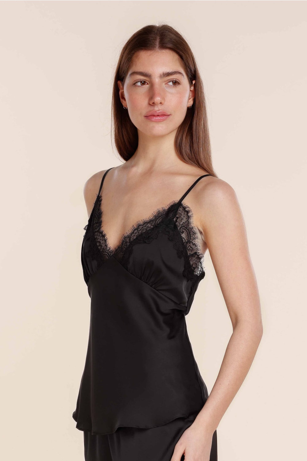 Woman wearing a black lace-trimmed nightgown against a beige background