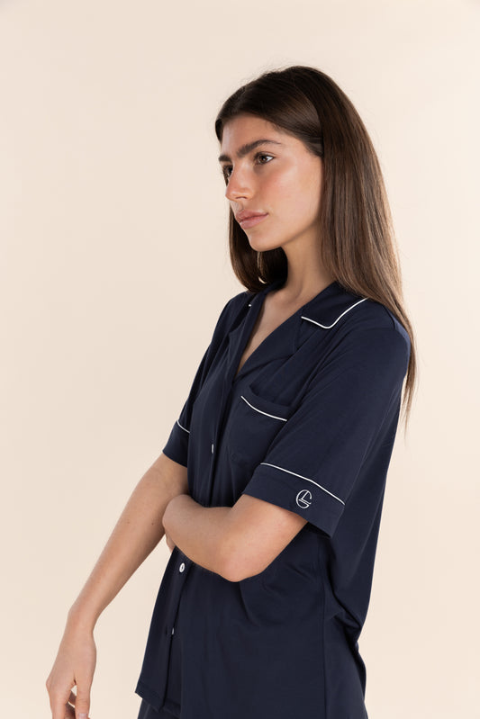 Woman wearing a navy blue shirt with white trim on a beige background