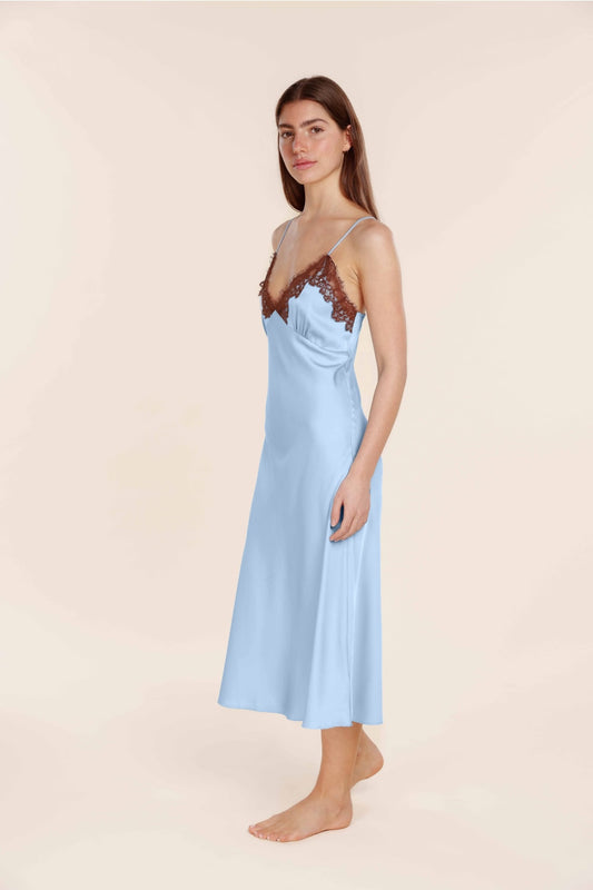 Woman wearing a light blue slip dress with lace details on a beige background