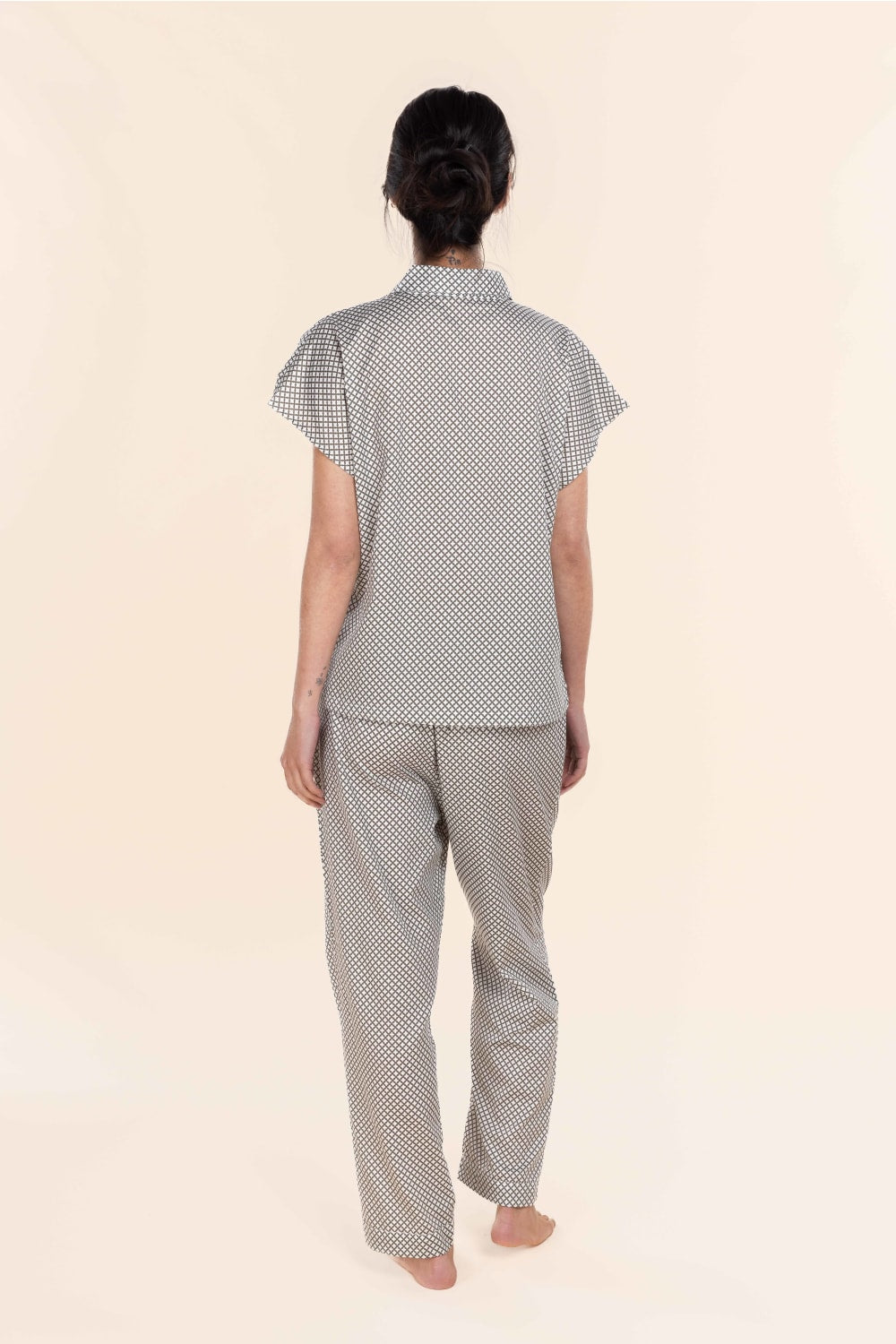 Person wearing a matching polka dot shirt and pants set on a beige background