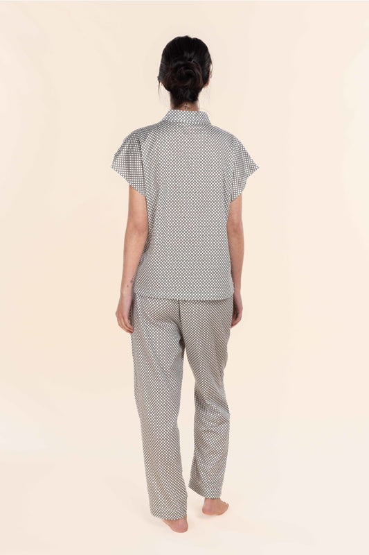 Person wearing a matching polka dot shirt and pants set on a beige background