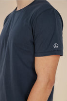 Navy blue t-shirt with a logo on the sleeve against a beige background