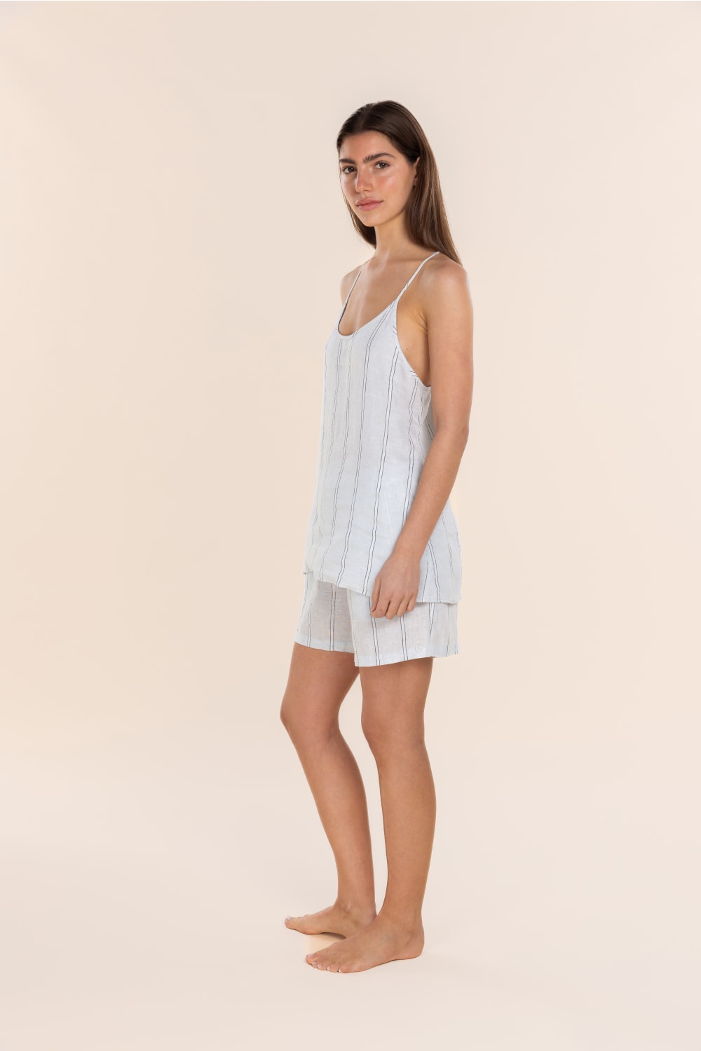 Woman wearing a light blue striped cami set on a beige background