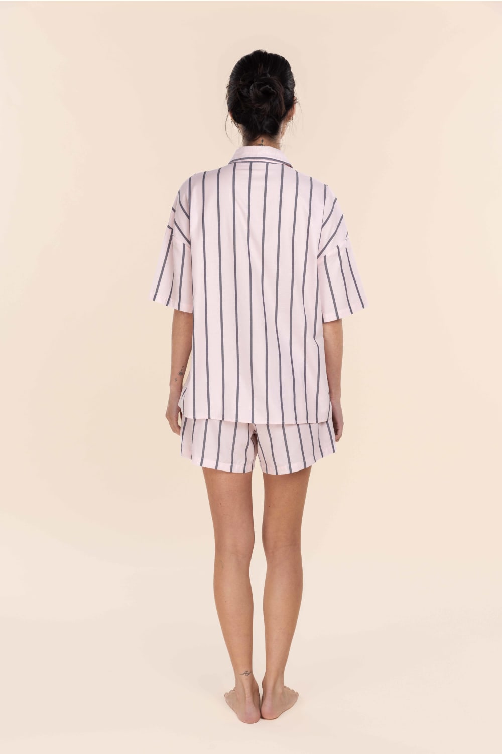 Person wearing a striped pajama set on a beige background