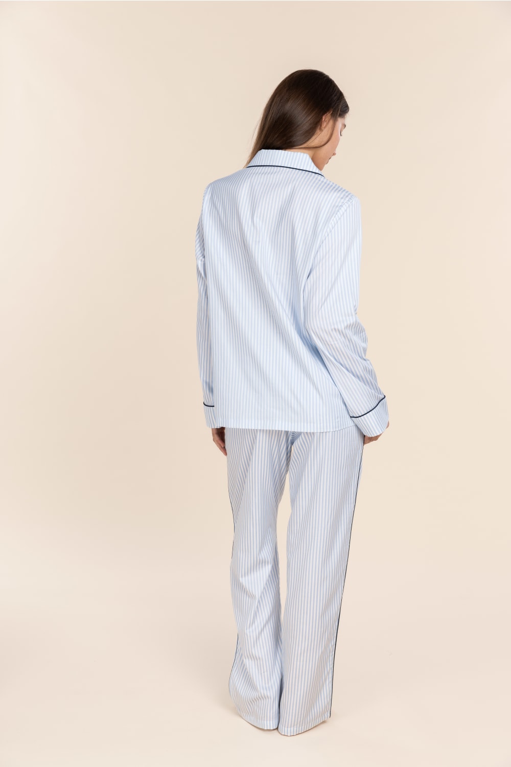 Person wearing a light blue striped pajama set on a beige background