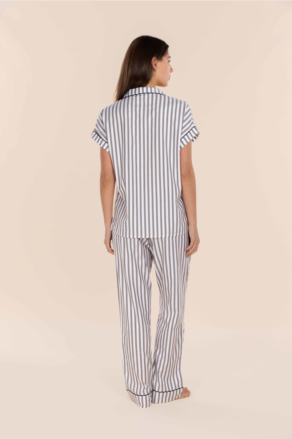 Woman wearing a striped pajama set on a beige background