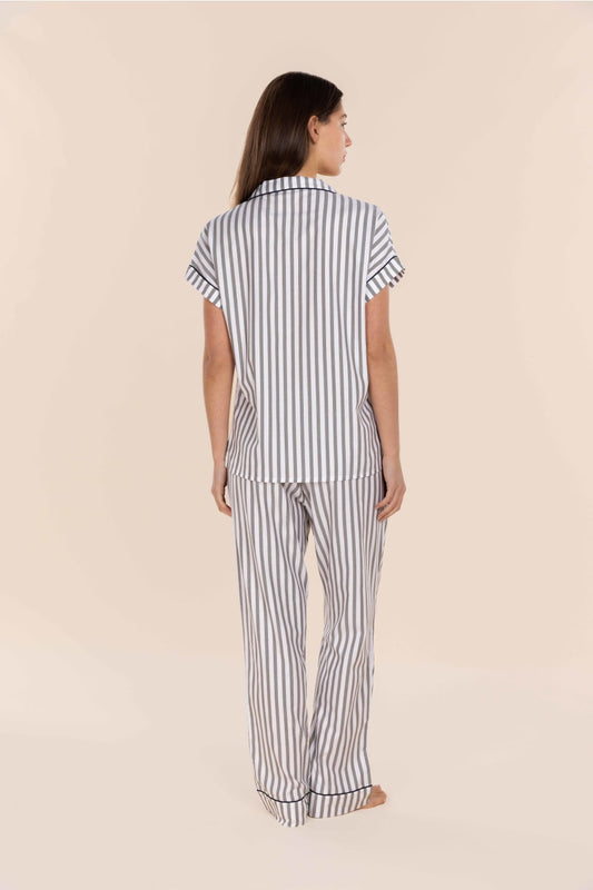 Woman wearing a striped pajama set on a beige background