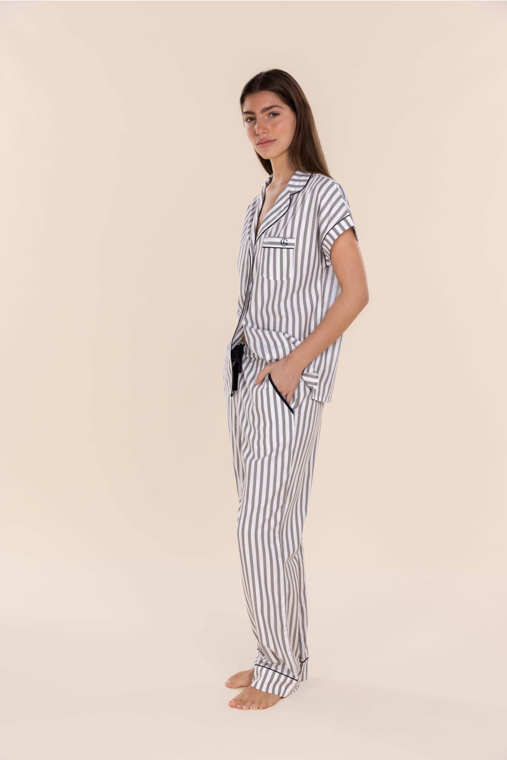 Woman wearing a striped pajama set on a beige background